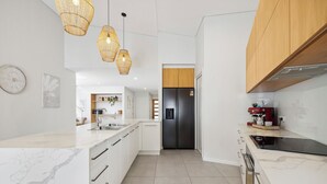 A modern kitchen with white cabinetry, a black refrigerator, and a coffee machine. - Oceanfront View Beachside Bliss – Ocean Views, Plunge Pool & Pet Friendly (Sapphire Beach)