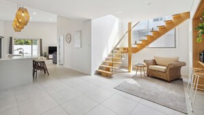 A spacious living area with a modern kitchen, a staircase, and a cozy seating area. - Oceanfront View Beachside Bliss – Ocean Views, Plunge Pool & Pet Friendly (Sapphire Beach)