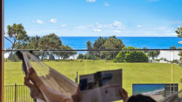 A person relaxing in a hammock with a view of a grassy area and the ocean. - Oceanfront View Beachside Bliss – Ocean Views, Plunge Pool & Pet Friendly (Sapphire Beach)