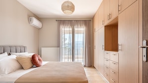 A bedroom with a bed, a wardrobe, and a view of the outdoors. - Horizon Apartment (Kefalonia)