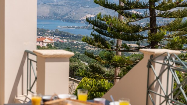 A table set with breakfast items and a scenic view of a lake and mountains. - Horizon Apartment (Kefalonia)