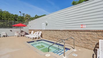 A pool area with lounge chairs and a red umbrella.