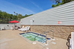 Un espace piscine avec des chaises longues et un parasol rouge.
