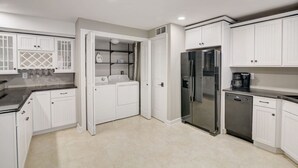 A modern kitchen with white cabinetry, stainless steel appliances, and a built-in washer and dryer. - Some'R on the Beach - Beachfront Condo for Six (Wisconsin Dells)