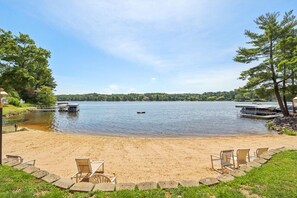 A lakeside view with a sandy beach, a dock, and a row of chairs. - Some'R on the Beach - Beachfront Condo for Six (Wisconsin Dells)