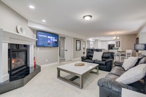 A modern living room with a fireplace, a flat-screen TV, a leather sofa, and a coffee table. - Some'R on the Beach - Beachfront Condo for Six (Wisconsin Dells)