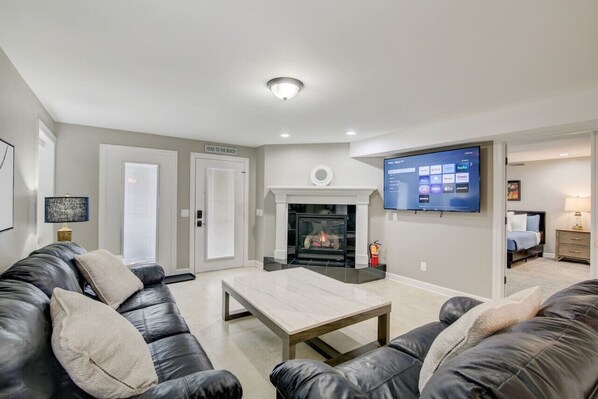 A modern living room with a fireplace, a flat-screen TV mounted on the wall, and a comfortable seating area with a leather sofa and a coffee table.