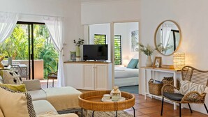 A well-lit living room with a television, wicker furniture, and a view of the outdoors.