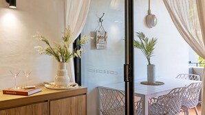 A modern dining area with a white table and chairs, a vase with flowers, a book titled "Australia," and a decorative sign on the wall.