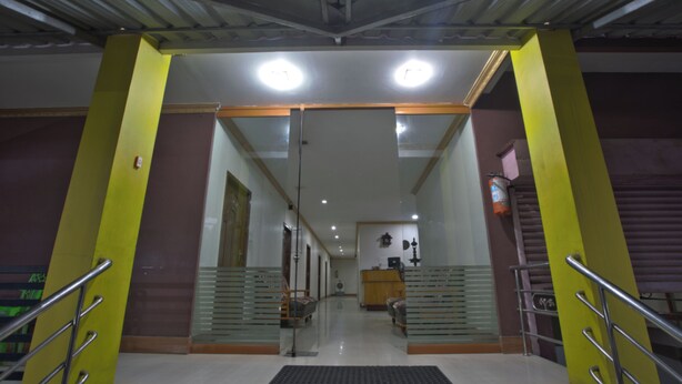 A hotel lobby with a reception desk, seating area, and a staircase leading to upper floors. - JAYA BHARATHI LODGE (Vilavancode)