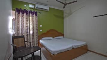 Une chambre à coucher comprenant un lit, une chaise, un ventilateur de plafond et un appareil de climatisation.