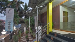 A hotel entrance with a checkered floor, potted plants, a staircase, and a signboard. - JAYA BHARATHI LODGE (Vilavancode)