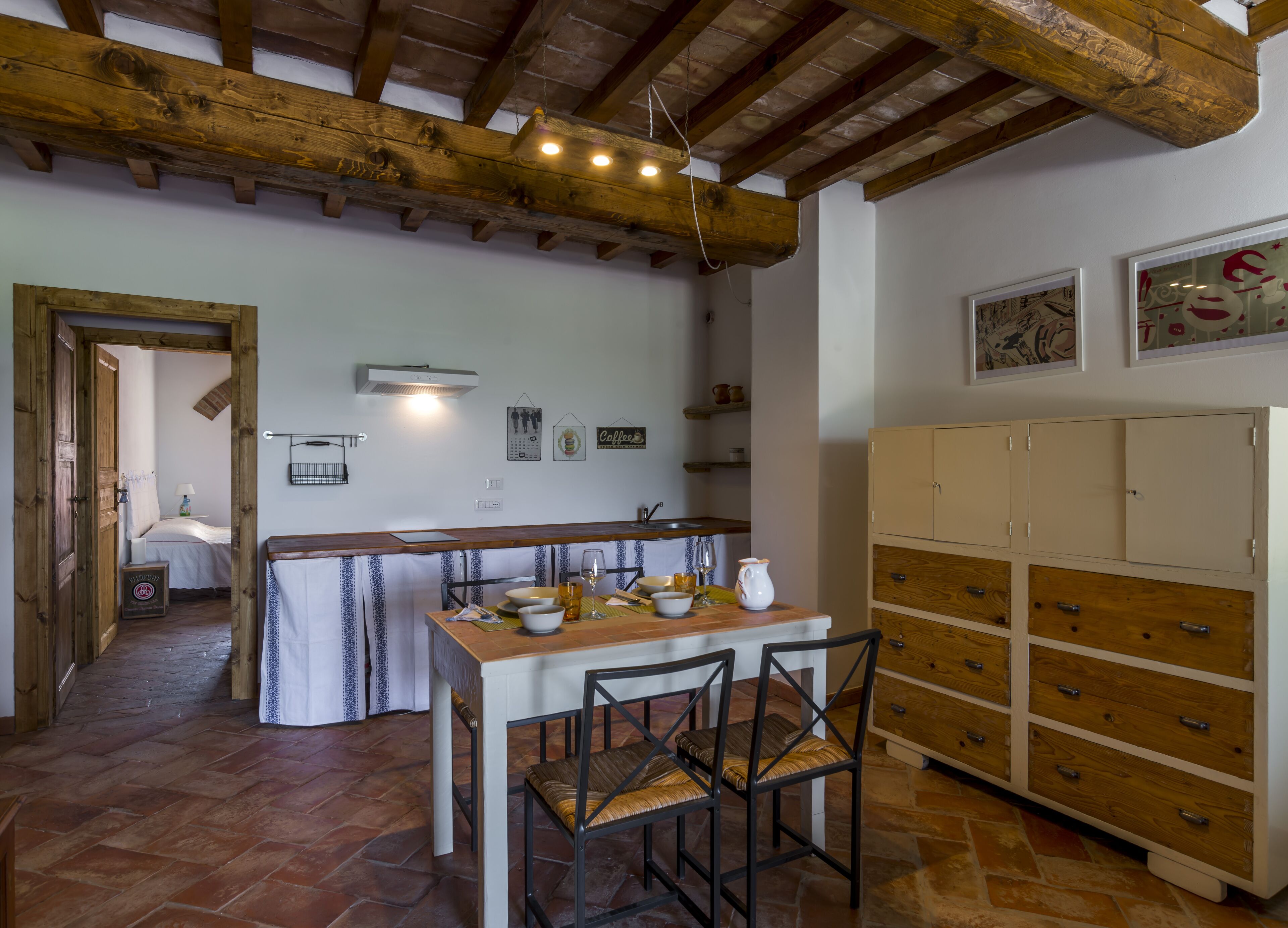 A rustic kitchen with a wooden table, chairs, and a cabinet.