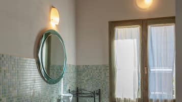 A bathroom with a tiled floor, a sink, a mirror, a window with curtains, and a radiator.