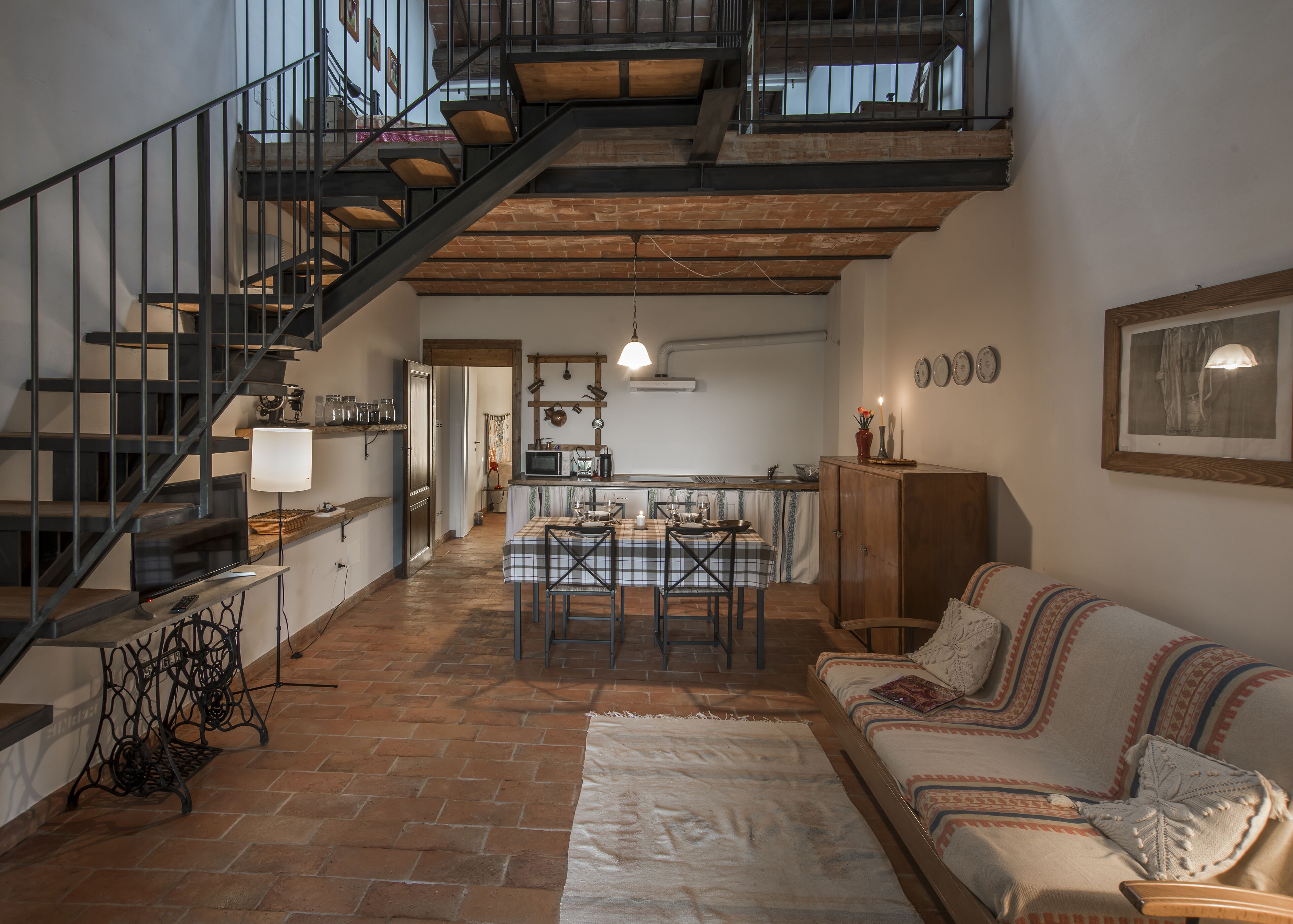 Un loft espaiós amb un sostre alt, parets de maó al descobert, una escala, una zona de dinar i un espai d'estar acollidor.