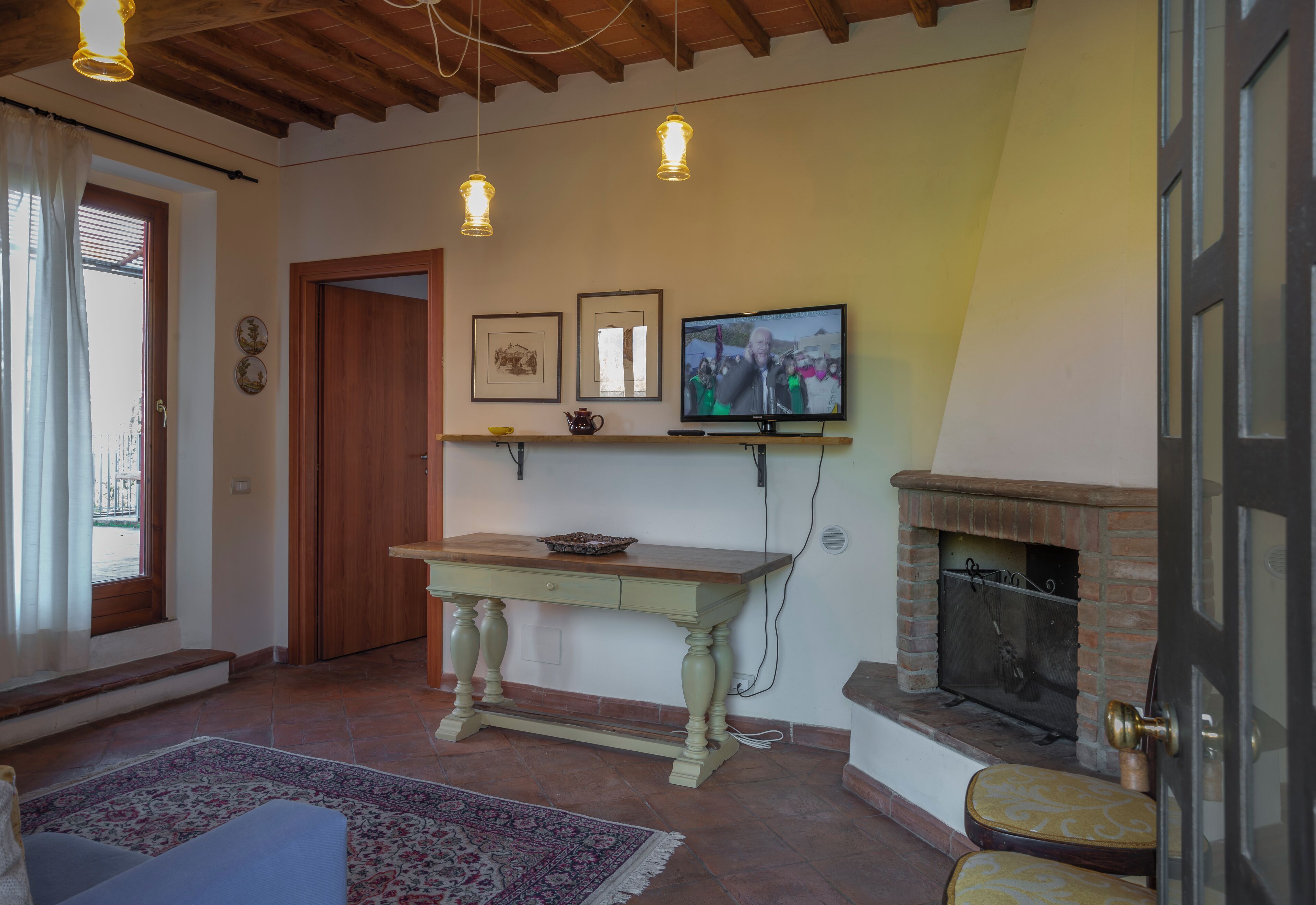 Een gezellige woonkamer met een houten tafel, een televisie en een open haard.