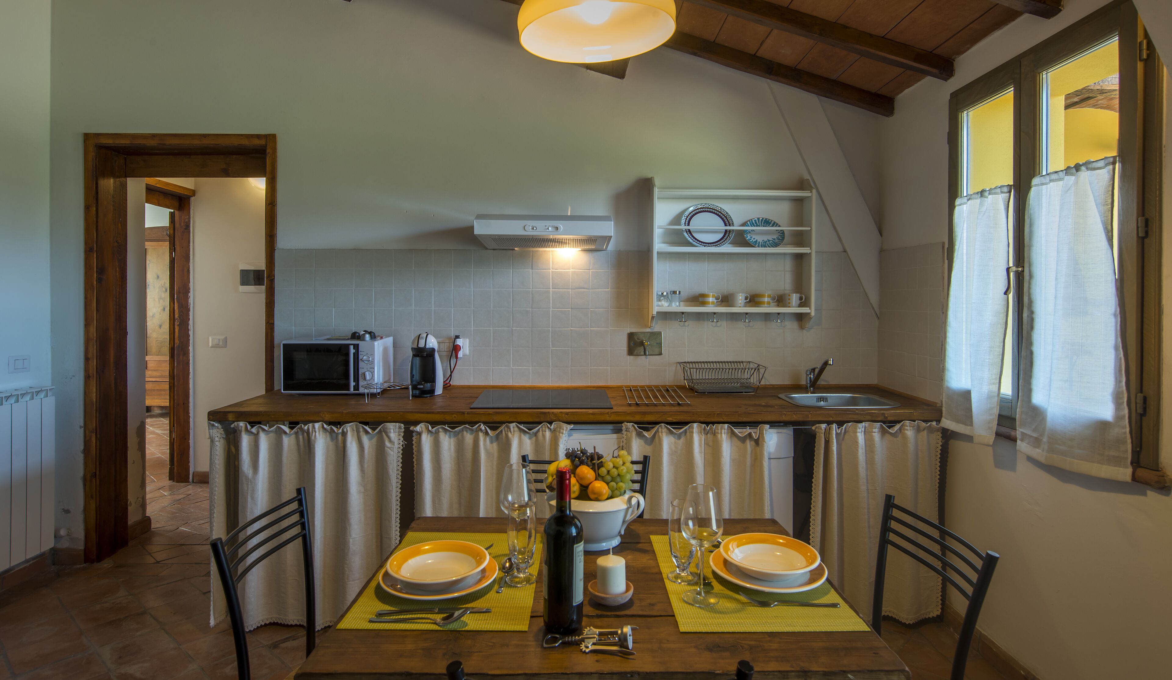 A kitchen with a dining table set for two, a microwave, and a coffee maker.