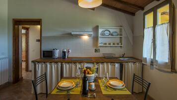 A kitchen with a dining table set for two, a microwave, and a coffee maker.