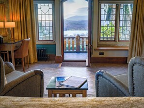 A room with a view of a lake, a wooden desk, two chairs, and a small table with a book. - Holbeck Ghyll Country House Estate (Windermere)