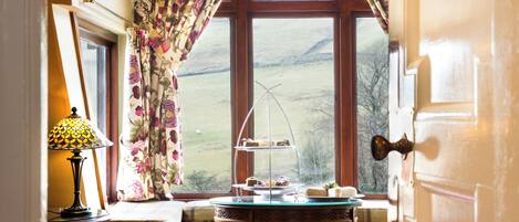 A room with a window, a table with a tray of food, a lamp, and a door.