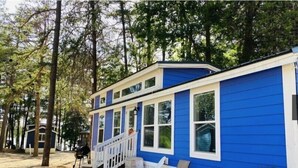 A blue cabin with white trim, a porch with white railings, and a small deck area. - Lakefront Two Bedroom Cabin #35 (Charlotte)