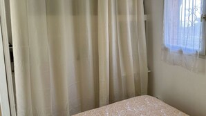 Ein Zimmer mit einem Bett, einem Fenster mit Blick und transparenten Vorhängen.