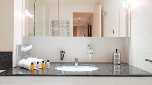 A modern bathroom with a marble sink, a large mirror, and a towel rack.