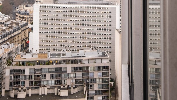 A view of the Eiffel Tower from a high-rise building, with a large white building in the foreground.