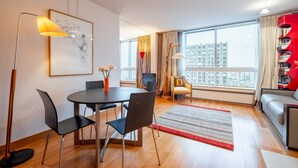 A modern living room with a dining area, large windows, and a view of the cityscape.