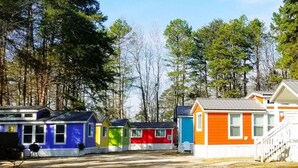 A row of colorful cabins with a dirt ground in front. - Lakefront Two Bedroom Cabin #37 (Charlotte)