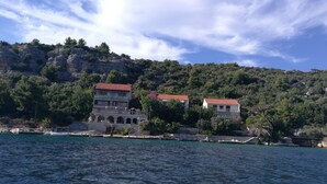 A coastal building with a restaurant sign, situated by a rocky shoreline with clear blue waters. - House VERONIKA,sea views, charming terrace,tranquility and natural beauty. (Drvenik Veliki)