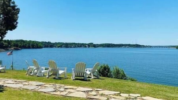 A lakeside view with white Adirondack chairs and a stone pathway. - Unique Lakefront House Boat at Long Cove Resort (Charlotte)