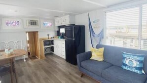 A compact living space with a kitchenette, a dining area, and a sofa with cushions. - Unique Lakefront House Boat at Long Cove Resort (Charlotte)