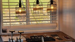 A kitchen with a wooden countertop, a ship's wheel, and three hanging light fixtures. - Unique Lakefront House Boat at Long Cove Resort (Charlotte)