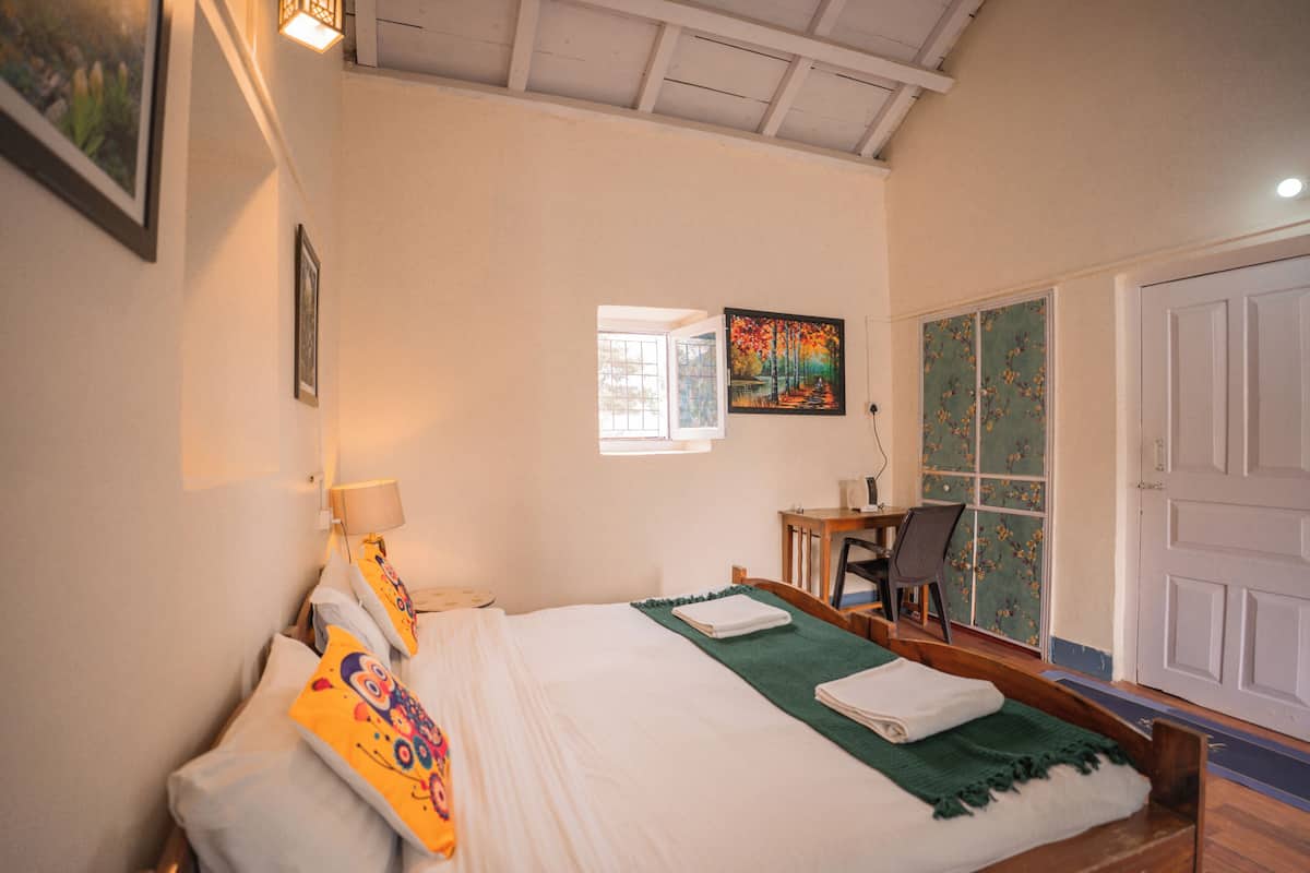 Un dormitorio con cama, escritorio, silla, ventana y puerta.