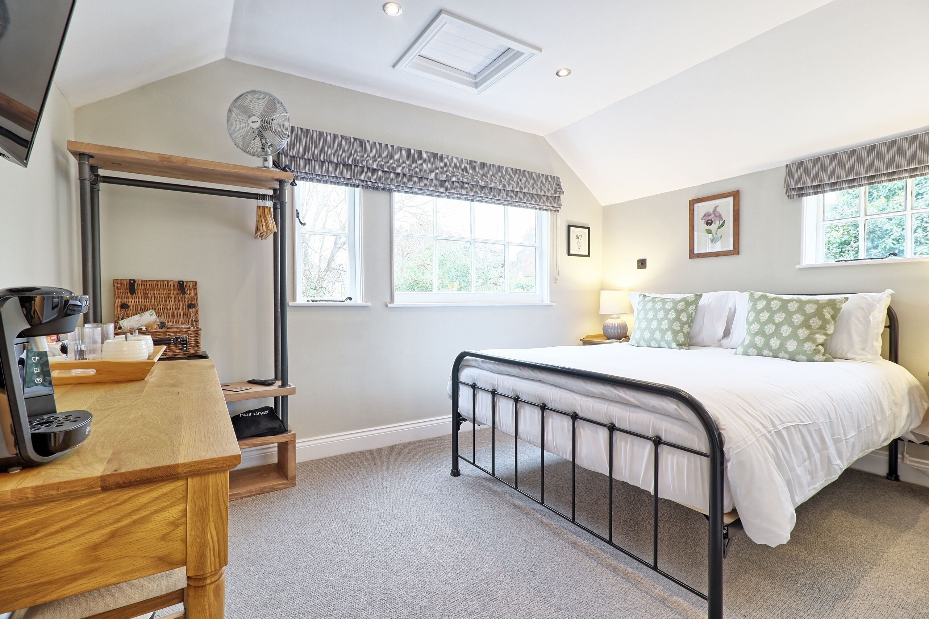 A bedroom with a bed, a desk, a mirror, and a window.