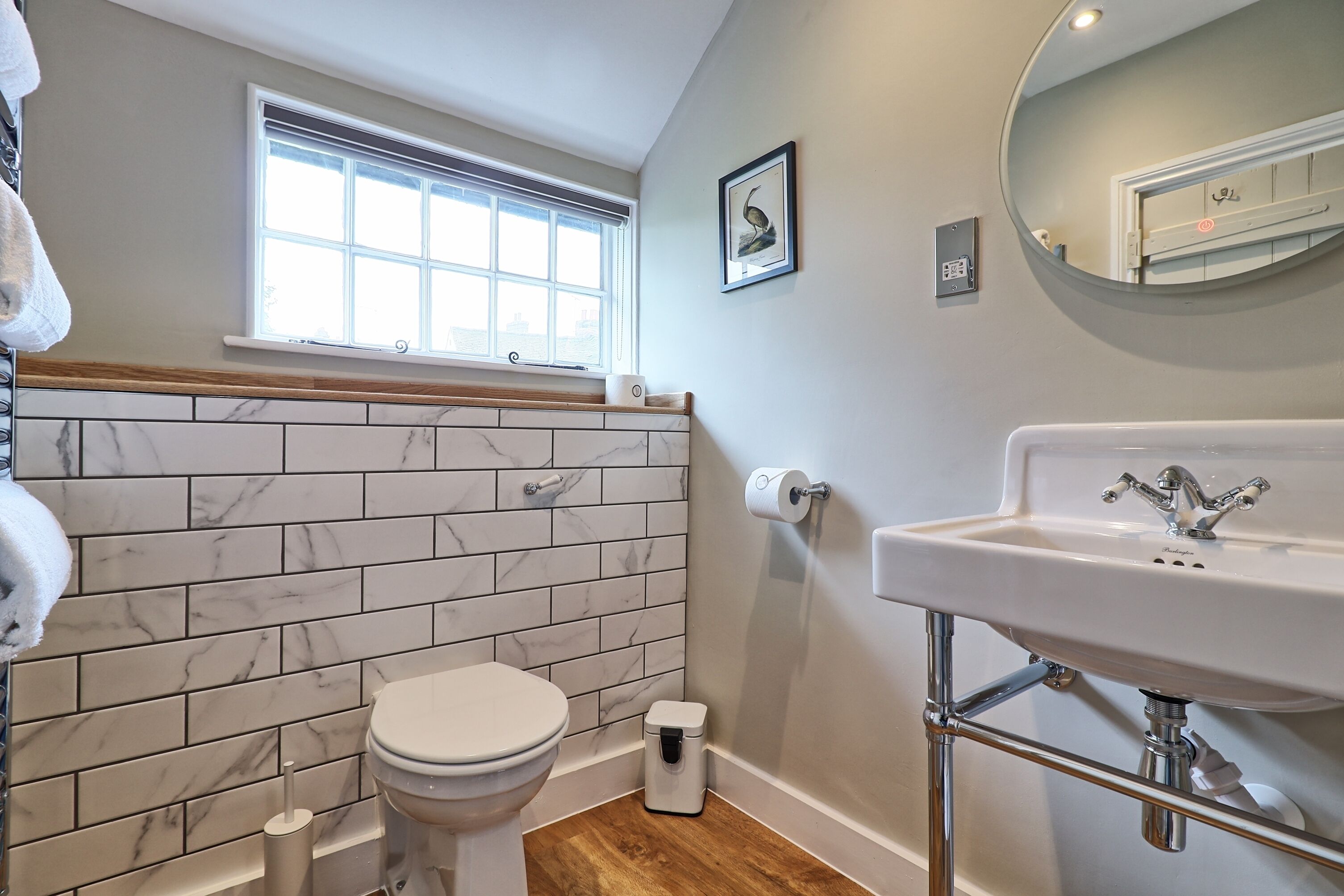 A bathroom with a toilet, sink, and window.