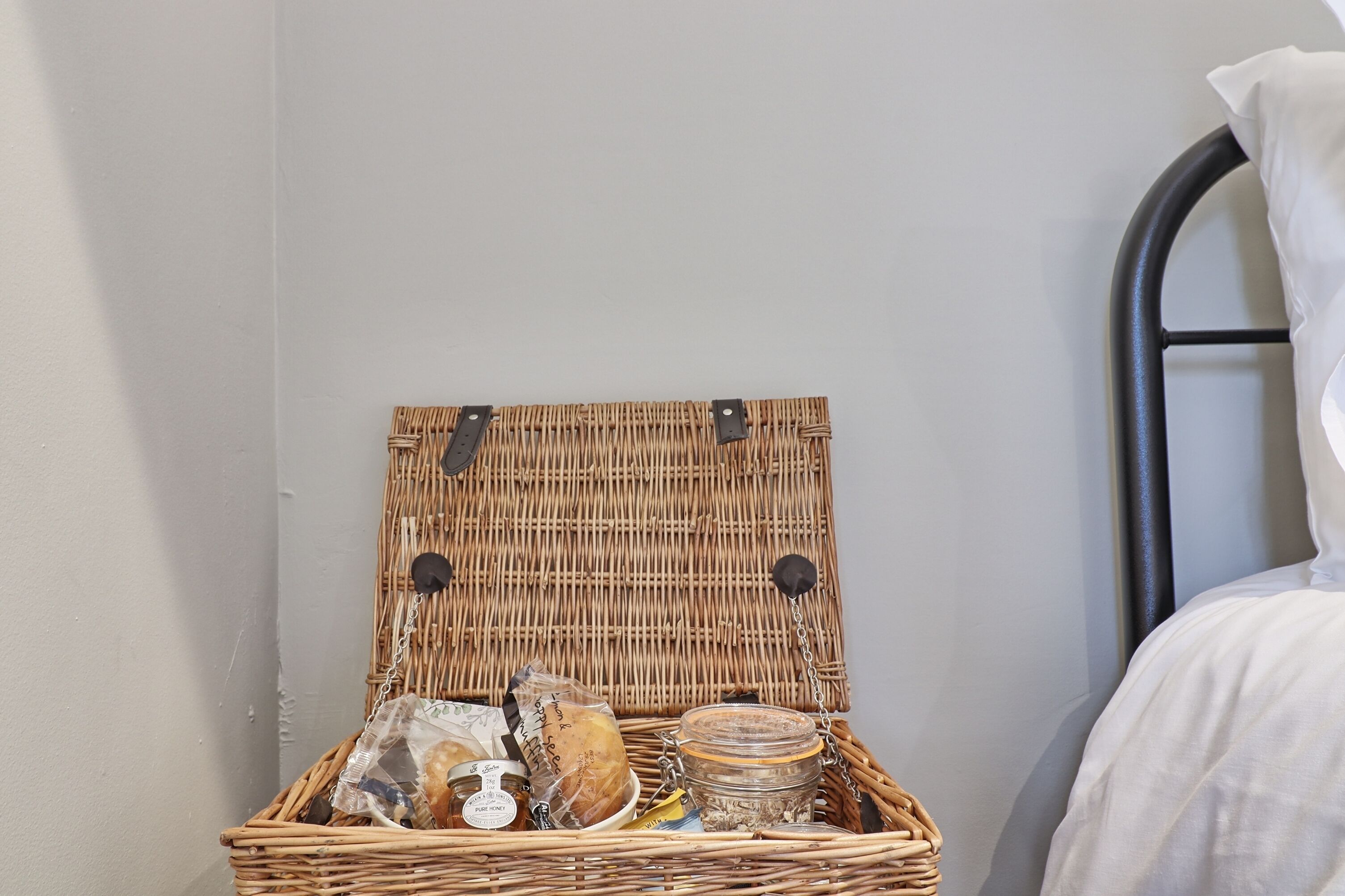 A wicker basket with a lid containing food items and a jar.