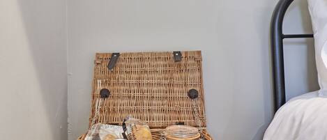 A wicker basket with a lid containing food items and a jar.