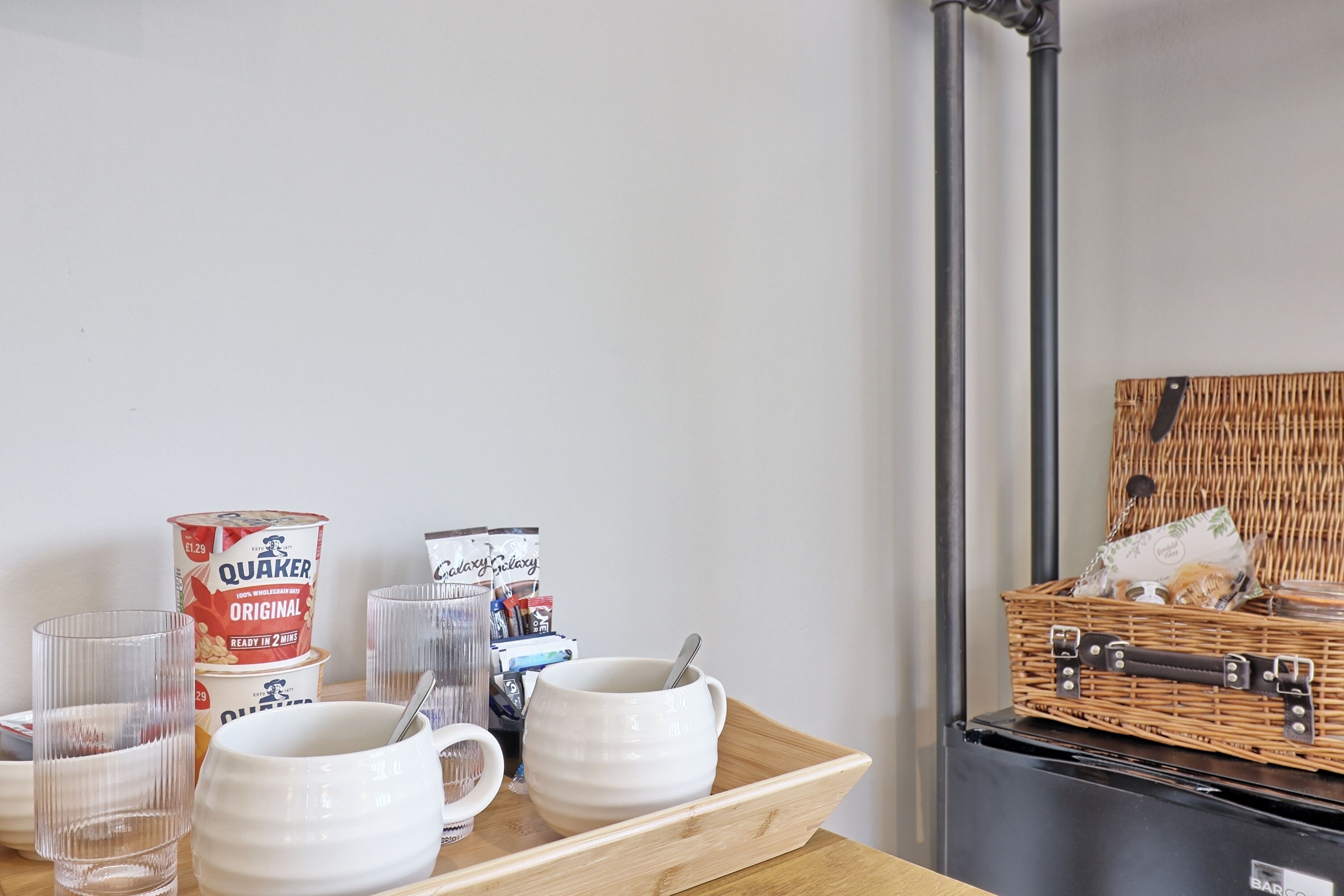 A breakfast tray with Quaker Oats and Galaxy microwave popcorn, a wicker basket with snacks, and a microwave.