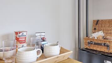 A breakfast tray with Quaker Oats and Galaxy microwave popcorn, a wicker basket with snacks, and a microwave.