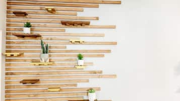 Pared con listones de madera horizontales y estantes con macetas pequeñas.