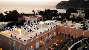 Una terraza en la azotea con mobiliario exterior, piscina y vistas al mar.