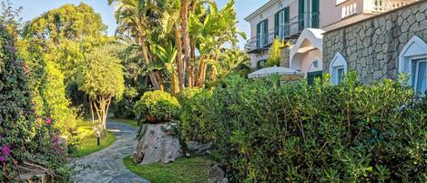 A stone pathway leading to a building with a stone facade and green shutters.