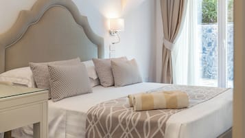 Un lit bien fait, agrémenté d’oreillers à motifs, une table de chevet et une lampe fixée au mur.
