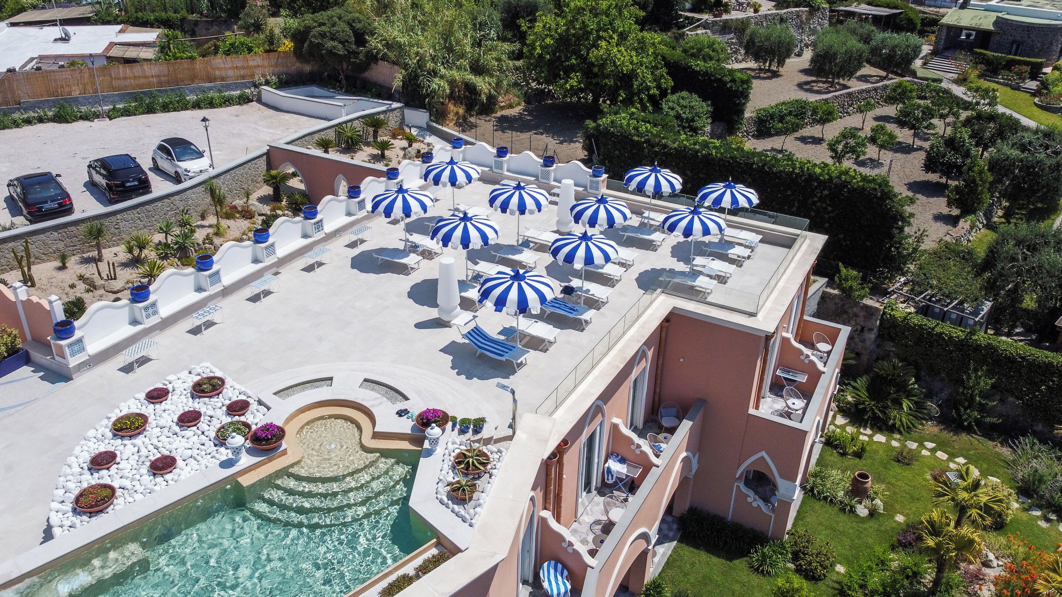 A rooftop pool area with multiple sun loungers and blue and white striped umbrellas.