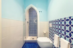 A bathroom with a shower, toilet, and patterned tiles.