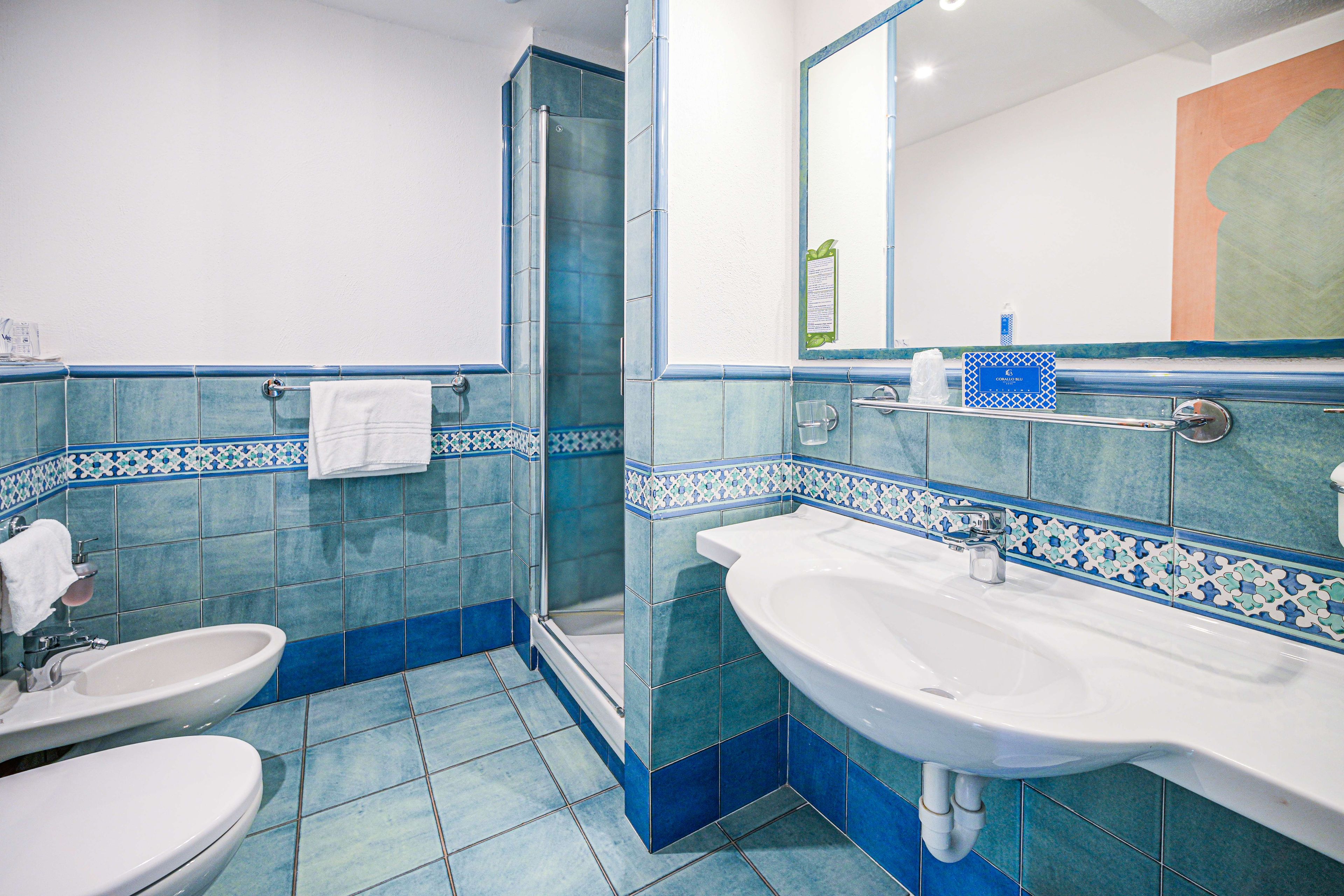 A bathroom with a glass shower enclosure, two sinks, and a toilet.