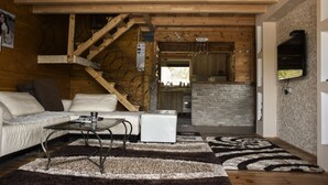 A cozy cabin interior with a sofa, coffee table, and a staircase leading to an upper level. - Genti House Ada Bojana (Ulcinj)