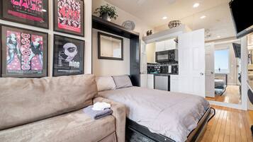 Une chambre avec un lit, un canapé, un miroir et un coin cuisine.